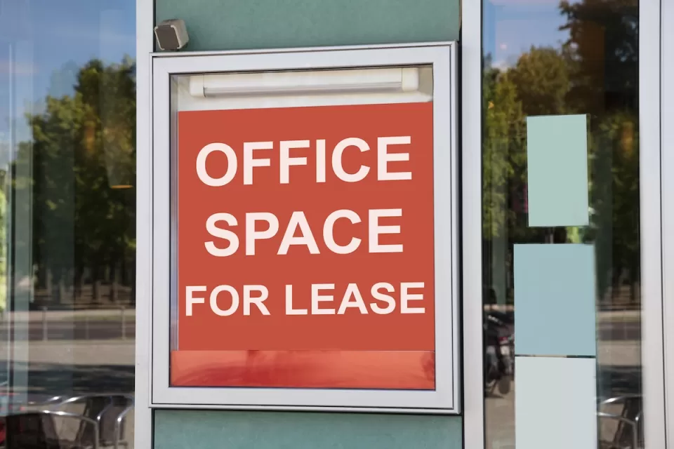 Close-up on red and white "Office space for lease" sign in window of office building.